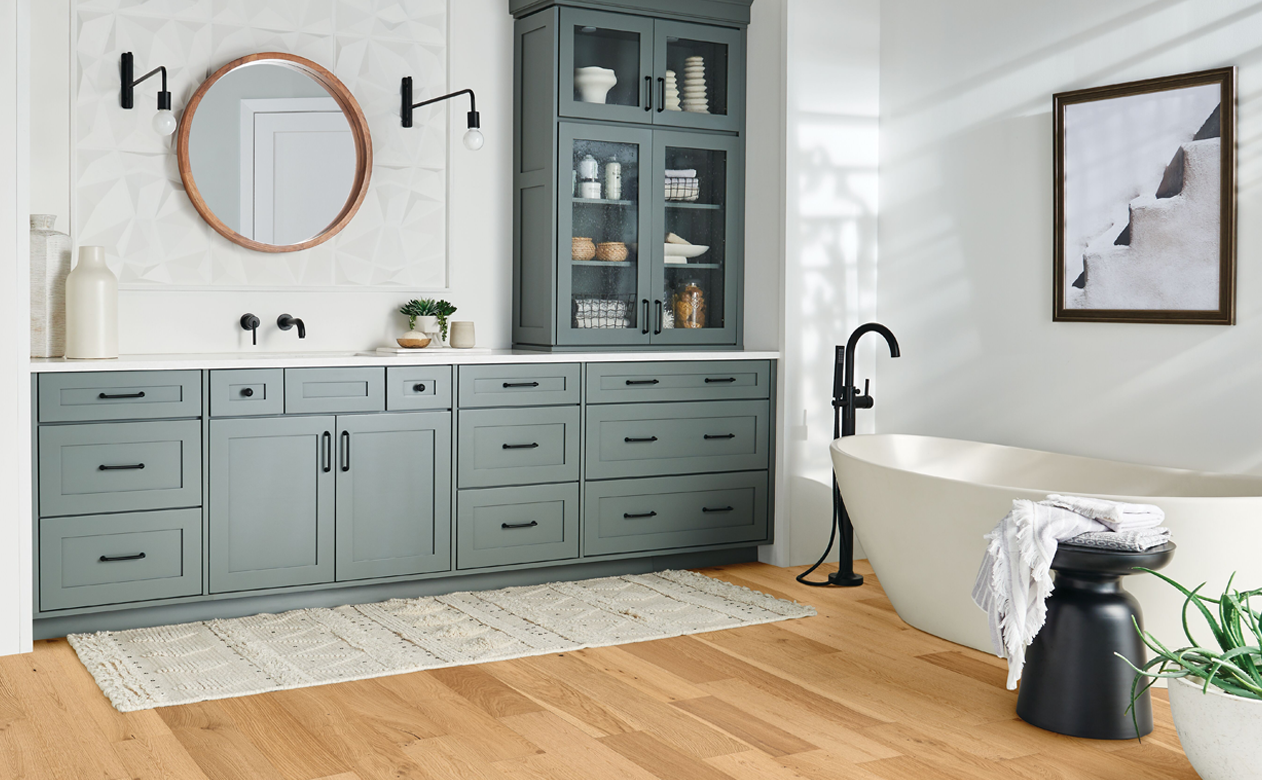 light wood flooring in bathroom with white countertops and soaker tub